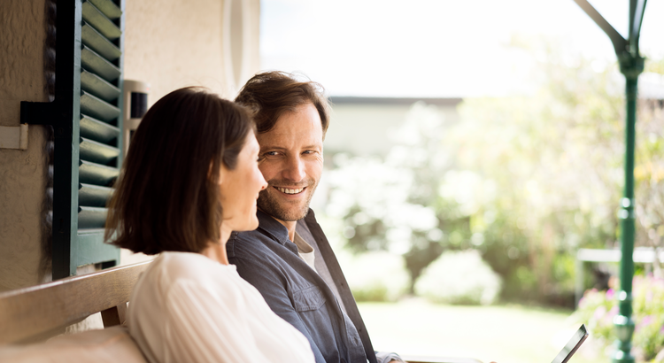 man and woman sitting on a porch bench smiling at each other