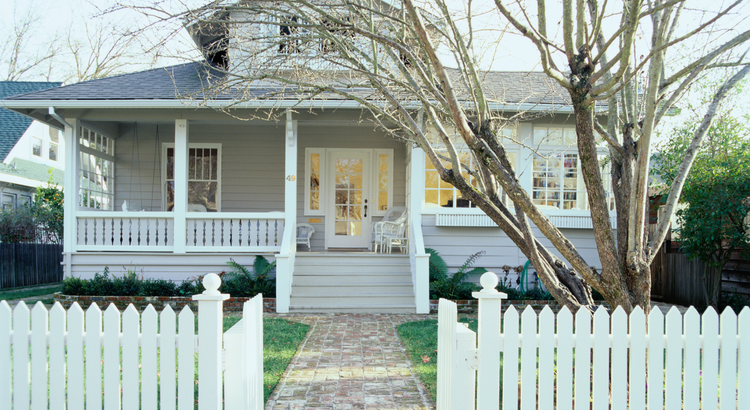front of a bungalow house with porch and white picket fence