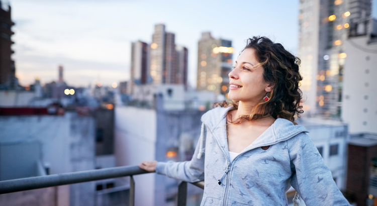 Woman standing on a balcony looking out at a city skyline